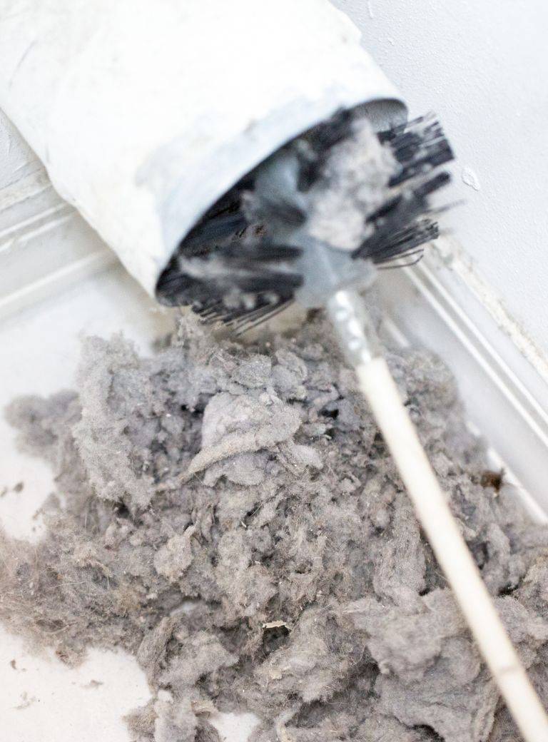A brush pulling a pile of lint out of a dryer vent